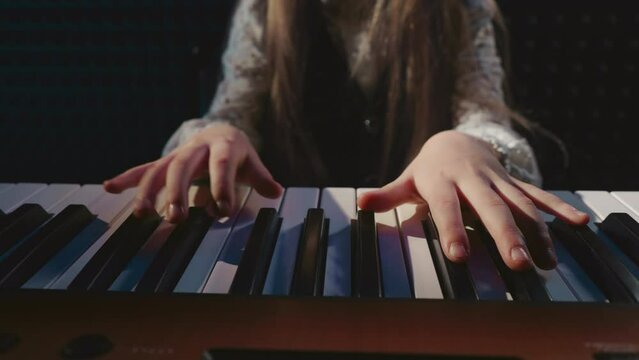 Student performs on piano in music academy. Petite girl learns sounds produced by keys of musical instrument in audio studio. Artistry in music