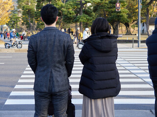 東京都の都心の交差点の横断歩道で信号待ちの男女の姿