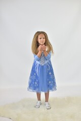 a girl with long hair and in a beautiful blue dress stands and holds her palms in front of her
