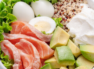 Salmon quinoa bowl with greens and vegetable on the wooden table. Balance in bowl. Top view.