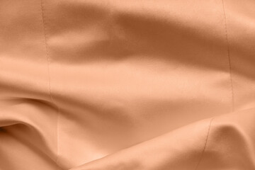 Peach fuzz satin fabric. Bridal wedding dress textile background.
