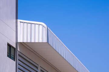 Aluminium steel roof eaves of new industrial building against blue clear sky background, low angle...