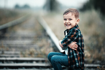 Lonely boy sits on railroad tracks. Mischievous man ran away from home. Bad boy.
