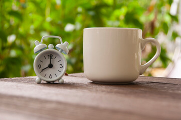 Alarm clock pointing at 8 o'clock with coffee cup on a bench. Copy space concept