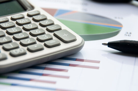 Analysis of data, chart and graphs with calculator and pen. Business finances concept
