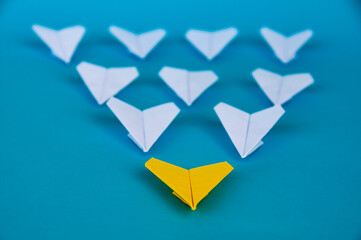 Yellow paper plane origami leading white planes on blue background. Leadership skills concept