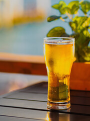 Transparent glass of beer stands on wooden table in open cafe. Low alcohol. Beer addiction. Background.