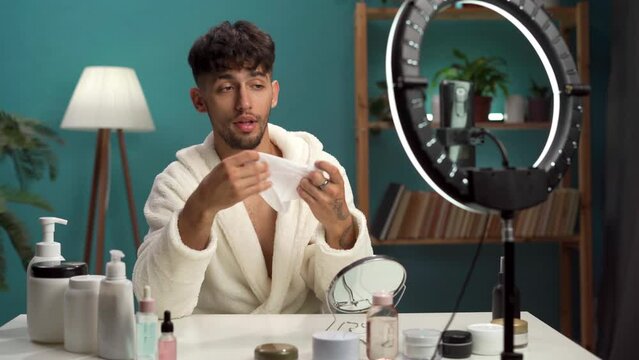 Male beauty blogger in a bathrobe running a blog about beauty and skin care records lessons in a live broadcast for social networks