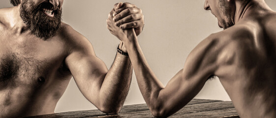 Arms wrestling thin hand, big strong arm in studio. Two man's hands clasped arm wrestling, strong...