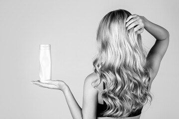Girl holds a bottle of cosmetics in her hand. Shampoo, gel. Woman long hair. Woman hold bottle...