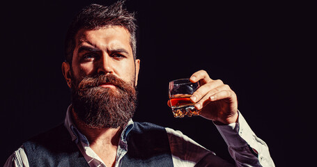 Man holding a glass of whisky. Sipping whiskey. Portrait of man with thick beard. Macho drinking....