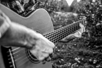 Man's hands playing acoustic guitar, close up. Acoustic guitars playing. Music concept. Black and...