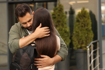 Long-distance relationship. Young couple with backpack hugging outdoors, space for text