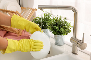 Woman washing bowl at sink in kitchen, closeup