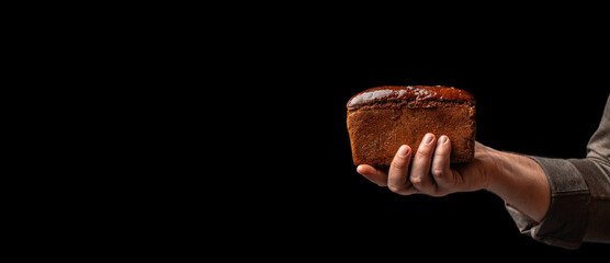 kraft square rye loaf of bread in hand on black background, Baking bread at home, Long banner...