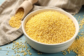 Millet groats in bowl on light blue wooden table, closeup
