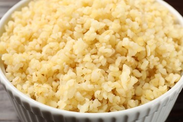 Delicious bulgur in white bowl, closeup view