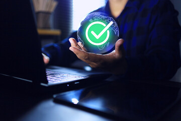 Hand holding globe and correct green checkmark while working on laptop computer screen represent to...