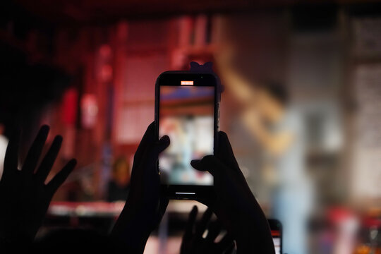 Person holding smartphone with background of concert