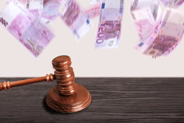 mallet gavel on courtroom or auction  table with 500 euro bills falling in motion blur