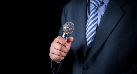 Man in business suit holding a microphone conducting a business interview, journalist reporting,...