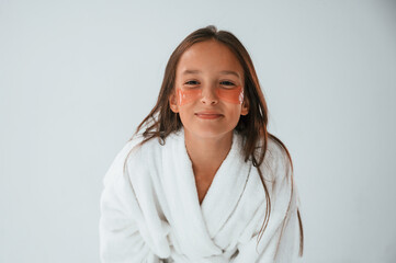 Standing, having fun, in white robe. With eye patches. Conception of beauty and self care. Young...