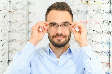 Healthcare, Eyesight And Vision Concept. Happy man choosing glasses at optics store, selective focus