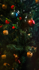 Fototapeta na wymiar Christmas tree with ornaments, Red and blue balls on fir tree and highlights. Decorated Christmas tree with glowing garlands of lights on blurred background. Concept of celebrating New Year