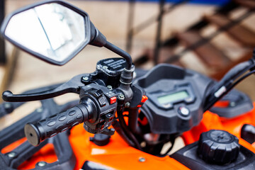 Close-up of the steering wheel of a orange colored quad bike. Selective focus.