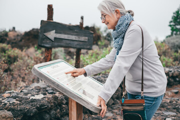 Smiling elderly woman visiting the island of Tenerife reads tourist information of the Chirche...