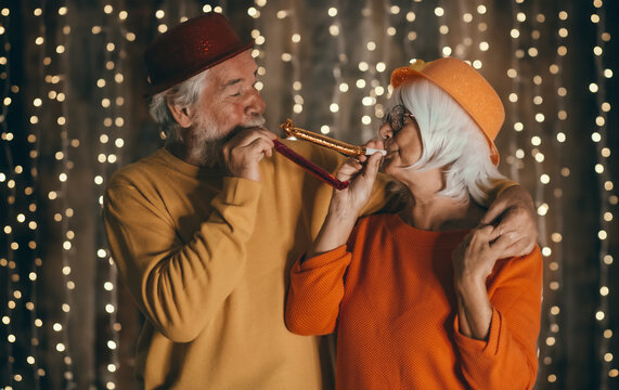 Celebrate event new year for couple of nice senior people - cheerful elderly caucasian man and woman having party by night. Happiness lifestyle for mature retired people, party lights