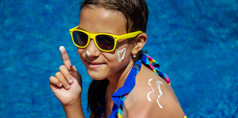 The child applies sunscreen. Selective focus.