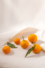 Vertical image of ripe whole clementines on the white tablecloth. Still life food composition
