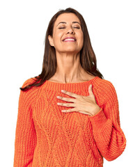 Elegant middle-aged Caucasian woman in studio setting laughs out loudly keeping hand on chest.