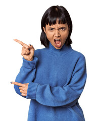 Young Hispanic woman with short black hair in studio pointing with forefingers to a copy space, expressing excitement and desire.