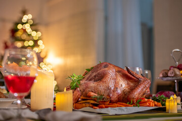 Turkey dinner Thanksgiving food. Man carry Christmas turkey food dinner Serve on table. Baked turkey chicken garnished with family Christmas tree and burning candles . Roasted turkey table setting