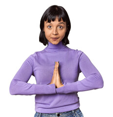 Young Hispanic woman with short black hair in studio praying, showing devotion, religious person...