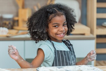 african afro black daughter kids sifting flour powder and sprinkling ingredients on massaging dough for bakery cooking. Black african daughter afro hair enjoy sifting flour wheat by sieve in kitchen - obrazy, fototapety, plakaty