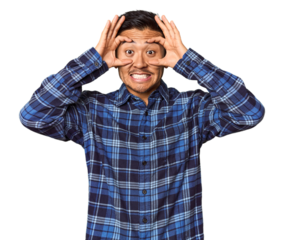 Young Chinese man in studio background keeping eyes opened to find a success opportunity.