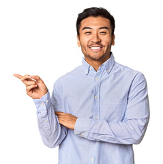 Young Chinese man in studio background smiling cheerfully pointing with forefinger away.