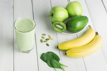 Green detox smoothie, blended vegetarian drink in a glass from spinach, apple, banana, kiwi,...