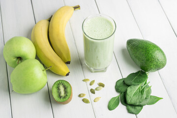 Green detox smoothie, blended vegetarian drink in a glass from spinach, apple, banana, kiwi,...