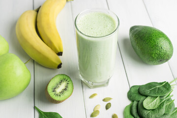 Green detox smoothie, blended vegetarian drink in a glass from spinach, apple, banana, kiwi,...