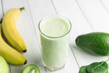 Green detox smoothie, blended vegetarian drink in a glass from spinach, apple, banana, kiwi,...