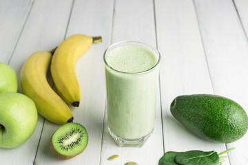 Green detox smoothie, blended vegetarian drink in a glass from spinach, apple, banana, kiwi,...
