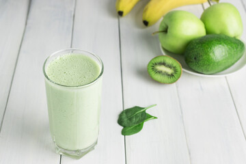 Green detox smoothie, blended vegetarian drink in a glass from spinach, apple, banana, kiwi,...
