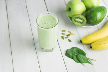 Green detox smoothie, blended vegetarian drink in a glass from spinach, apple, banana, kiwi,...