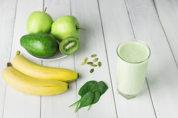 Green detox smoothie, blended vegetarian drink in a glass from spinach, apple, banana, kiwi,...