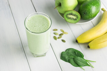 Green detox smoothie, blended vegetarian drink in a glass from spinach, apple, banana, kiwi,...
