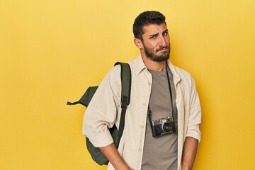 Fototapeta premium Young Hispanic travel photographer poses confused, feels doubtful and unsure.